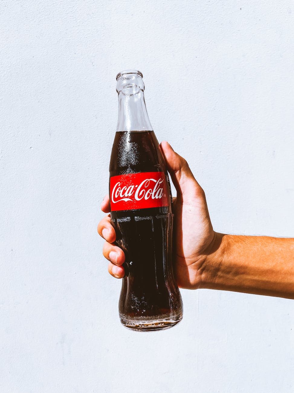 man holding a cold coca cola in a glass bottle